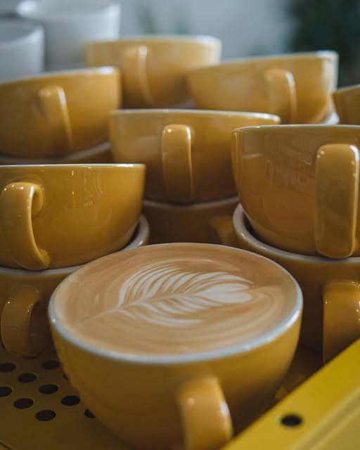 Latte art in ochre cups on La Marzocco